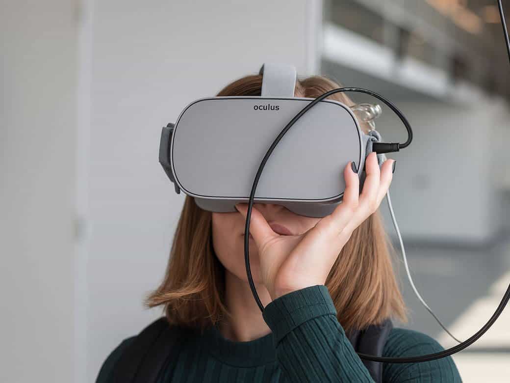 نص بديل للصورة: شخص يستخدم نظارة Oculus للواقع الافتراضي في بيئة داخلية حديثة.